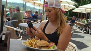 A young person captures their meal and shares it online. Outside eatery or cafe.